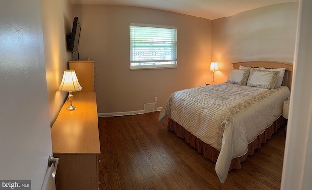 bedroom with baseboards, visible vents, and wood finished floors