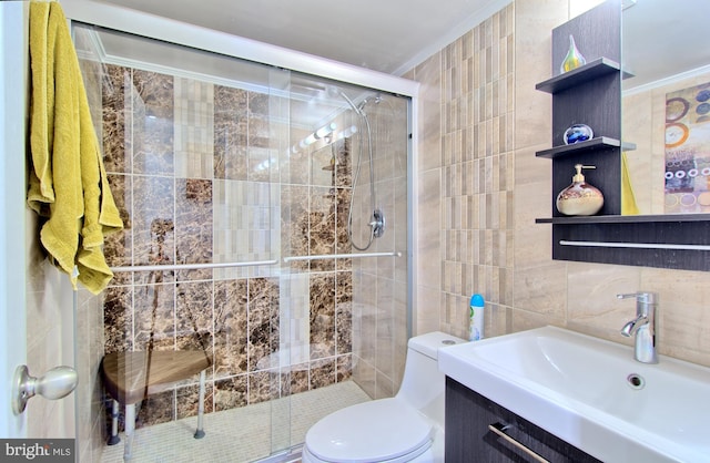bathroom featuring toilet, a stall shower, tile walls, vanity, and ornamental molding