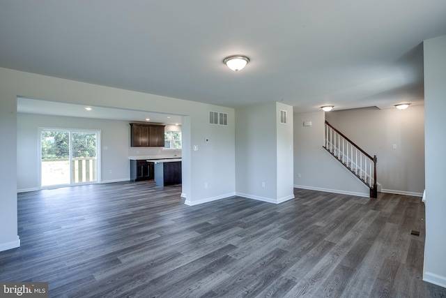 unfurnished living room featuring baseboards, stairway, visible vents, and dark wood-type flooring