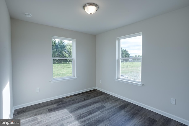 unfurnished room featuring baseboards and dark wood finished floors