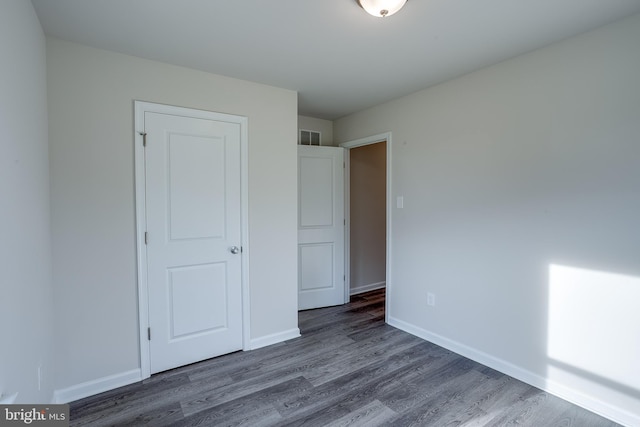 unfurnished bedroom featuring visible vents, wood finished floors, and baseboards
