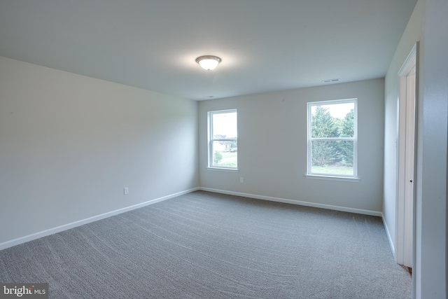carpeted spare room featuring baseboards and visible vents