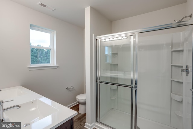 full bathroom with toilet, wood finished floors, a stall shower, visible vents, and vanity