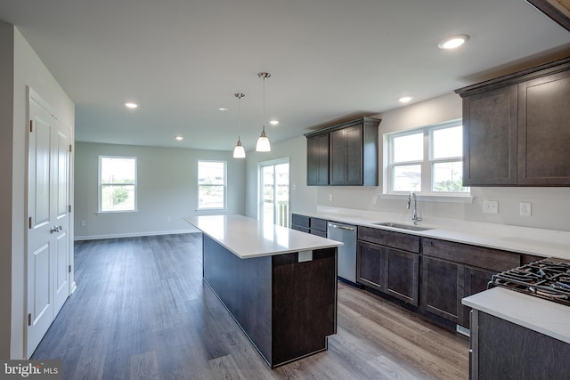 kitchen featuring dishwasher, a kitchen island, wood finished floors, and a sink