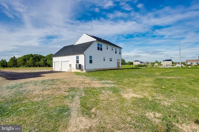 view of home's exterior with roof with shingles, driveway, a garage, a lawn, and central AC unit