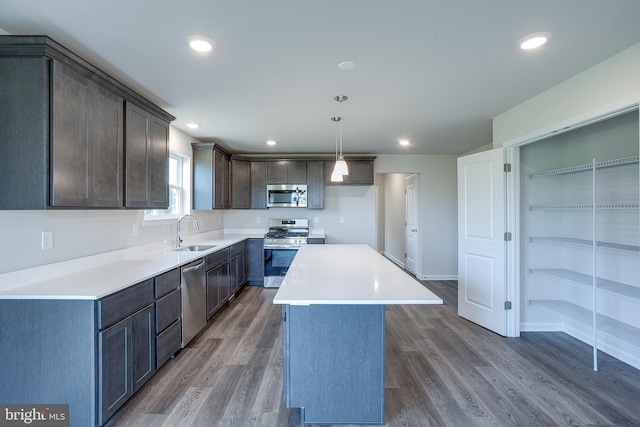 kitchen featuring a sink, stainless steel appliances, a kitchen island, and wood finished floors