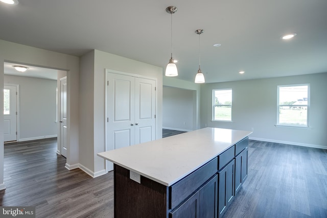 kitchen featuring a center island, pendant lighting, dark wood-style flooring, baseboards, and light countertops