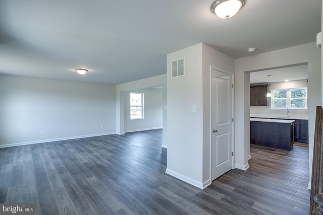 spare room featuring baseboards, dark wood finished floors, visible vents, and a sink