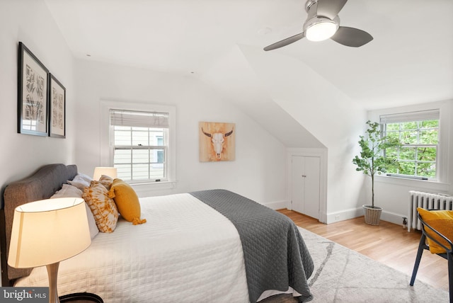 bedroom featuring radiator, wood finished floors, vaulted ceiling, a ceiling fan, and baseboards