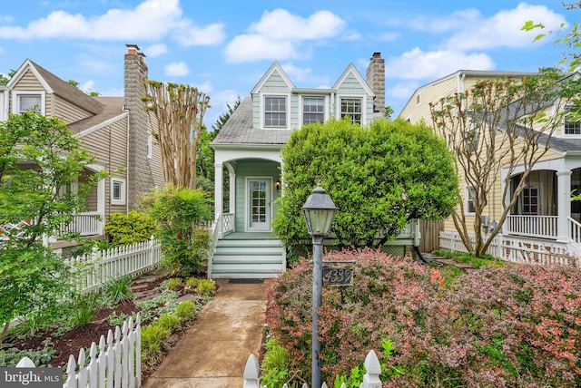 new england style home with covered porch, a chimney, and fence