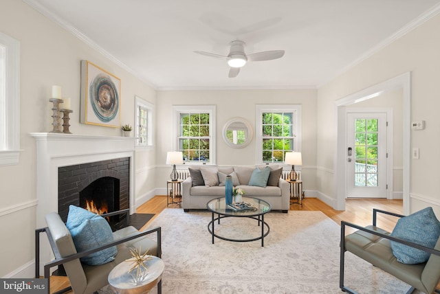 living area featuring plenty of natural light, wood finished floors, a ceiling fan, and a brick fireplace