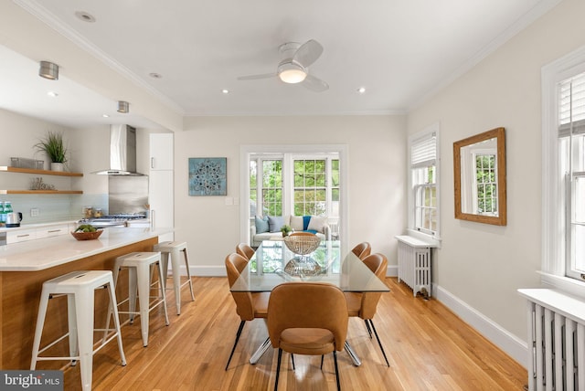 dining room featuring light wood finished floors, a ceiling fan, and ornamental molding