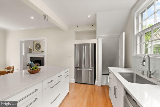 kitchen featuring a sink, appliances with stainless steel finishes, white cabinetry, modern cabinets, and light wood-style floors