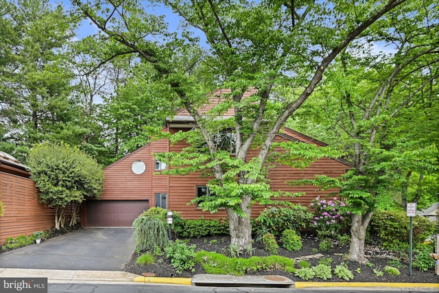 view of home's exterior featuring an attached garage and asphalt driveway