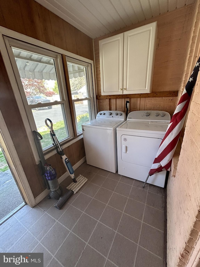 laundry room with washing machine and dryer, wooden ceiling, dark tile patterned floors, wooden walls, and cabinet space