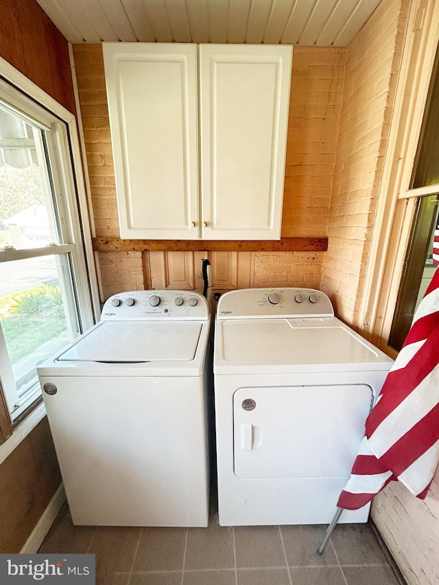 laundry room with cabinet space, independent washer and dryer, wood walls, and tile patterned flooring