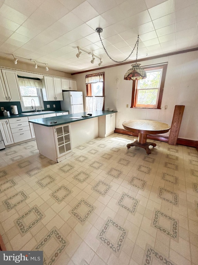 kitchen with a sink, freestanding refrigerator, dark countertops, and track lighting
