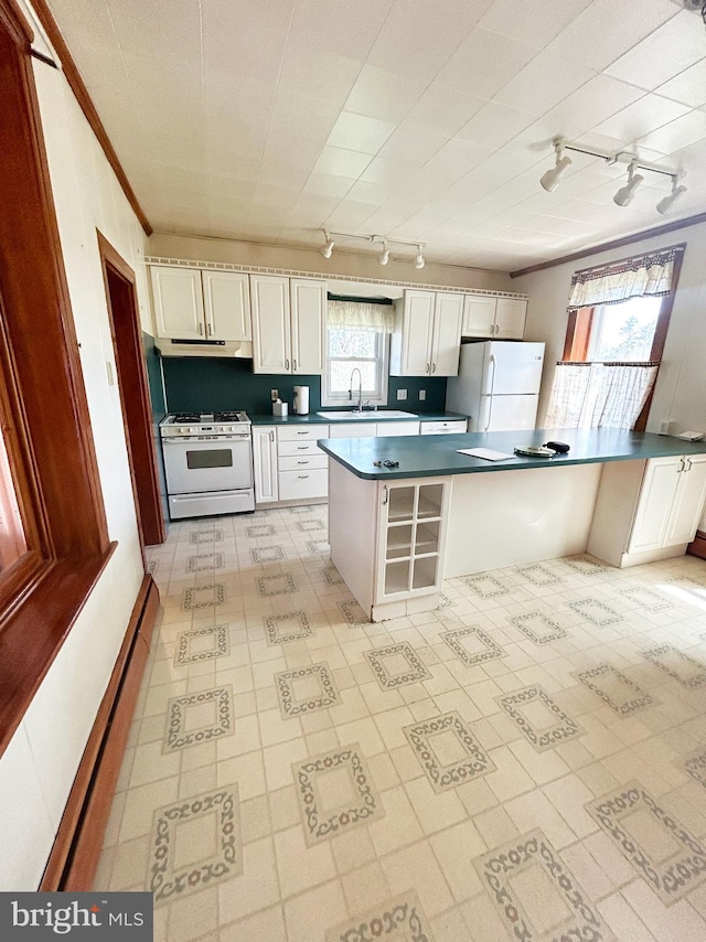 kitchen featuring a sink, white appliances, dark countertops, and track lighting