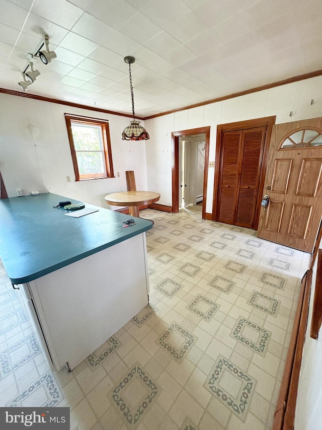 kitchen with light floors, a peninsula, ornamental molding, and hanging light fixtures
