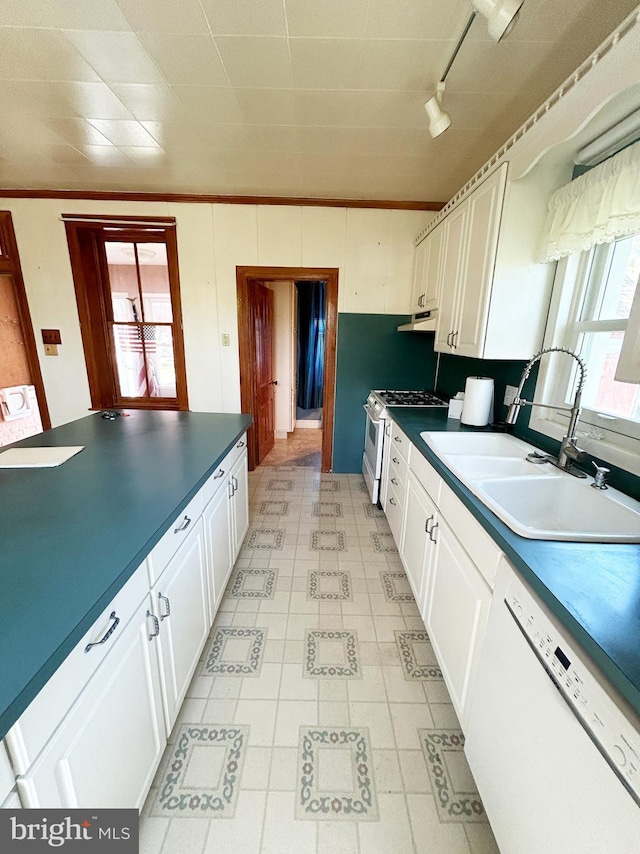 kitchen with a wealth of natural light, white appliances, dark countertops, and a sink