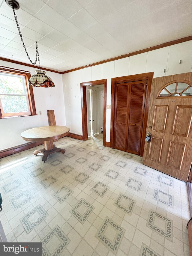 unfurnished dining area with crown molding, light floors, wooden walls, and baseboards