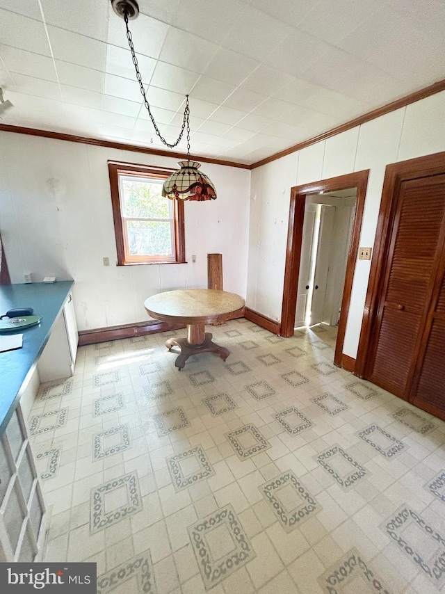 unfurnished dining area with crown molding, light floors, and baseboards