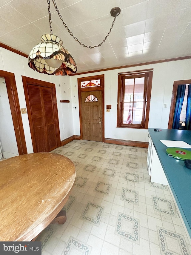 foyer with ornamental molding, light floors, and baseboards