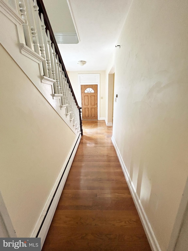 hallway featuring wood finished floors, stairway, baseboards, and baseboard heating