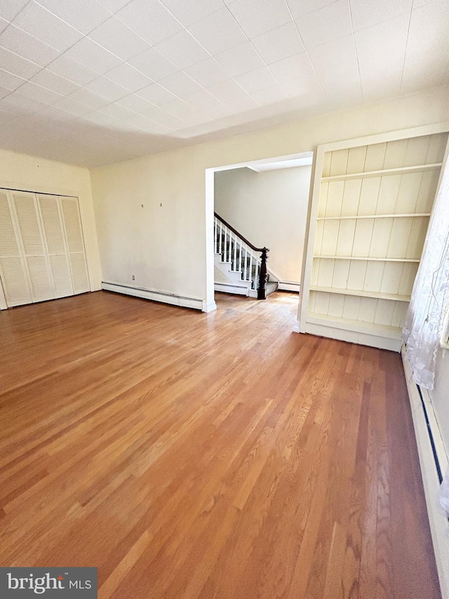 interior space featuring stairway, baseboard heating, and wood finished floors