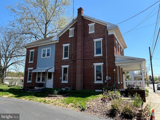 view of front facade featuring a chimney and brick siding