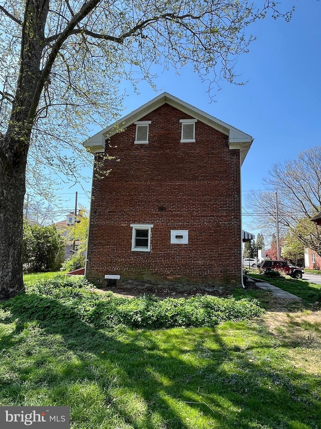 view of property exterior with a lawn and brick siding