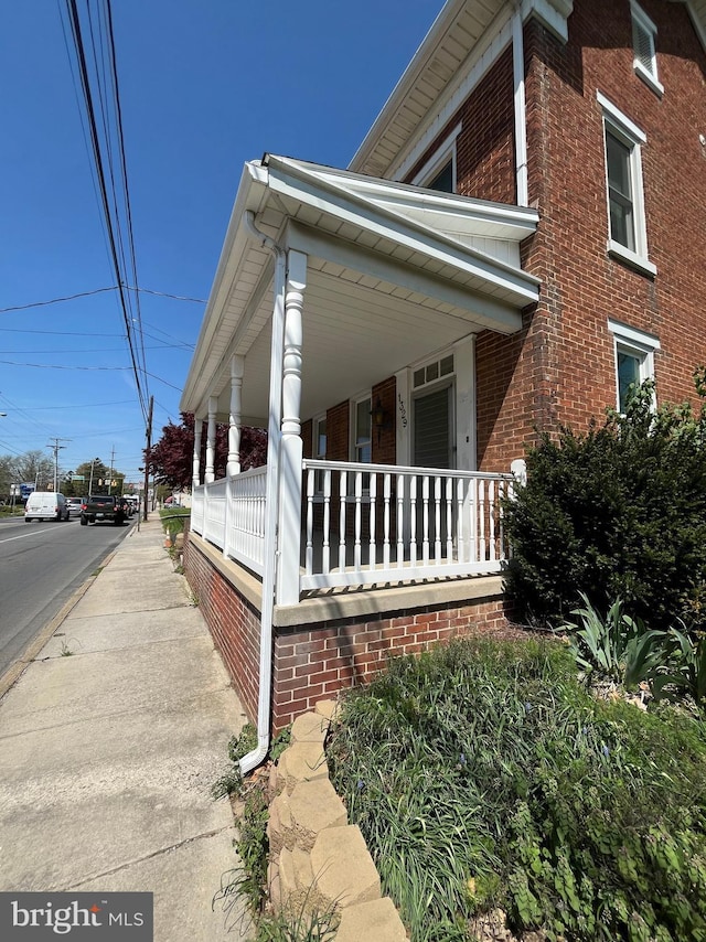 view of home's exterior with brick siding and covered porch