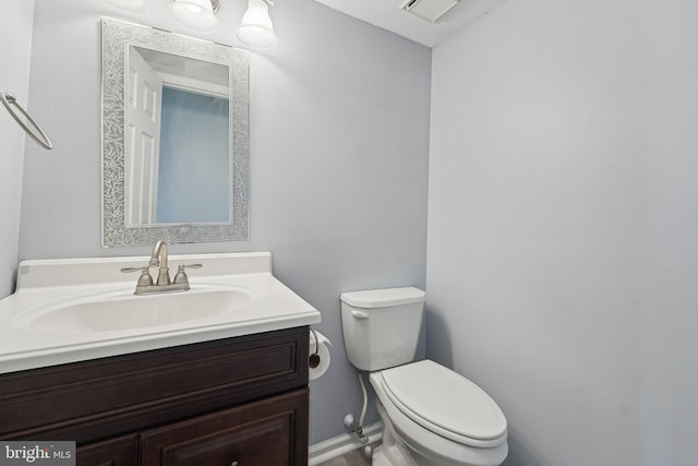 half bath with toilet, vanity, and baseboards