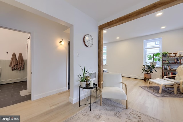 living area with a baseboard heating unit, beam ceiling, recessed lighting, and wood finished floors