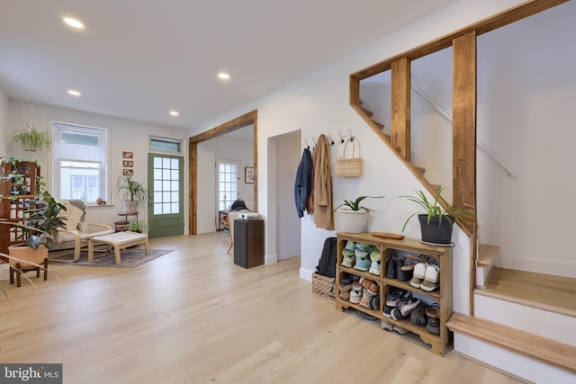 interior space with light wood finished floors, stairs, baseboards, and a healthy amount of sunlight