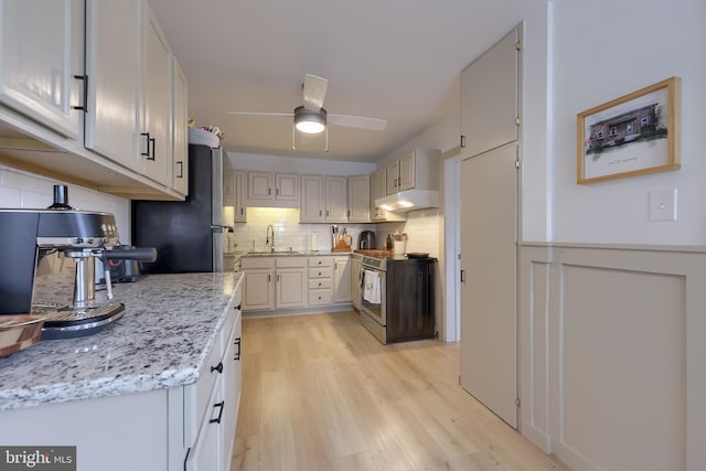 kitchen featuring a sink, tasteful backsplash, appliances with stainless steel finishes, ceiling fan, and light wood-style floors