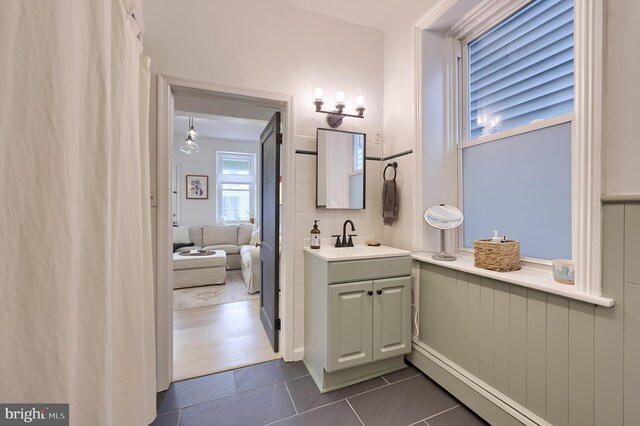 ensuite bathroom featuring a baseboard radiator, connected bathroom, tile patterned flooring, and vanity