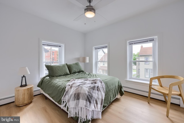 bedroom with wood finished floors and a baseboard radiator