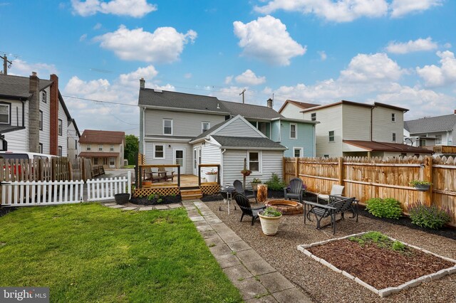rear view of property with a deck, a residential view, a fire pit, and a lawn