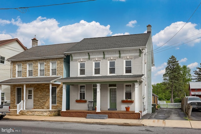 view of front of property with stone siding, a porch, and a chimney
