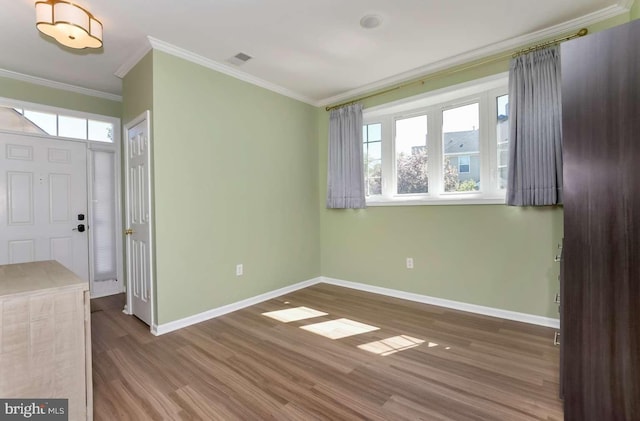 interior space with baseboards, visible vents, crown molding, and wood finished floors