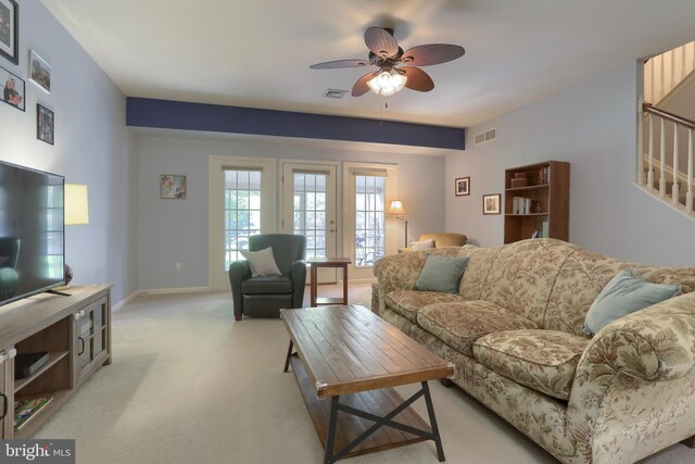 living room with ceiling fan, light carpet, stairway, and baseboards