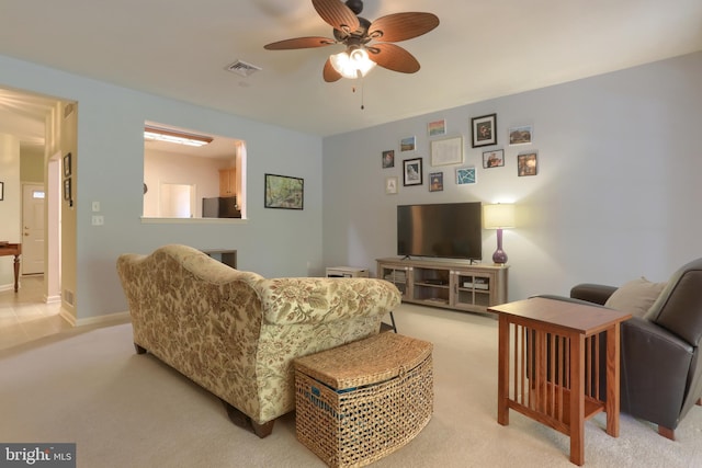 living room featuring light colored carpet, a ceiling fan, and baseboards