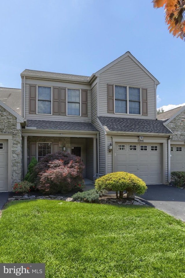 view of front of house with driveway, a front lawn, an attached garage, a shingled roof, and stone siding