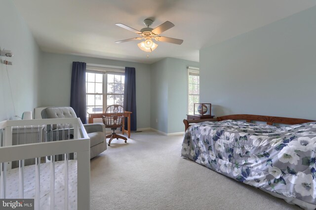 carpeted bedroom with multiple windows, baseboards, and a ceiling fan