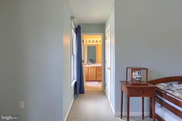 hall with light colored carpet and baseboards