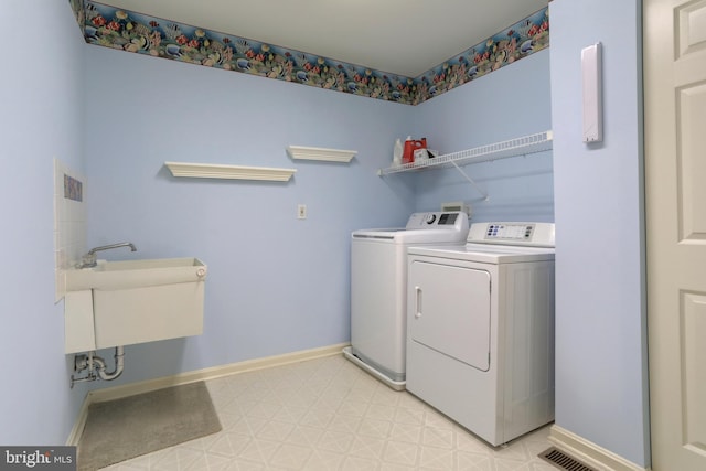 clothes washing area featuring separate washer and dryer, light floors, and baseboards
