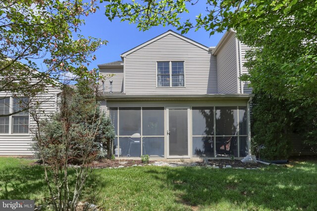 rear view of property featuring a sunroom and a lawn