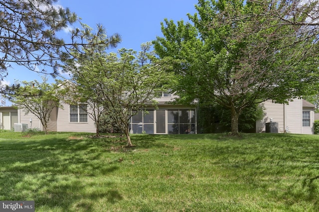 view of green lawn featuring central AC and a sunroom