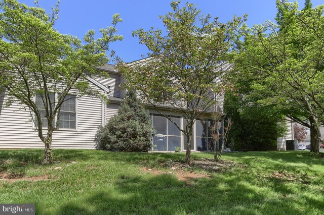 back of property featuring a sunroom and a lawn